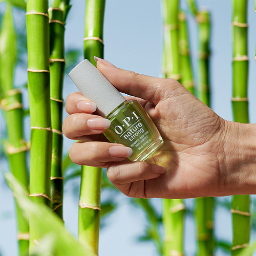 A hand holds OPI Nature Strong Top Coat