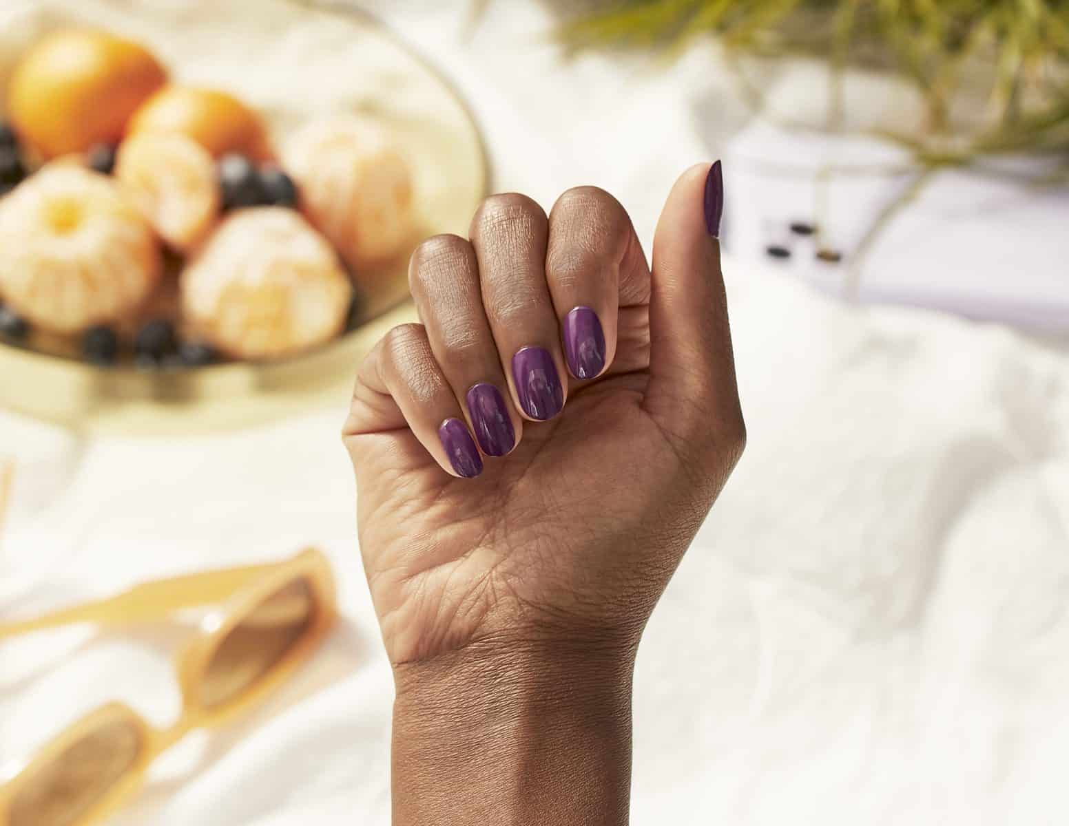A hand with painted nails in the "N00berry" shade from the Palette Xbox collection from OPI