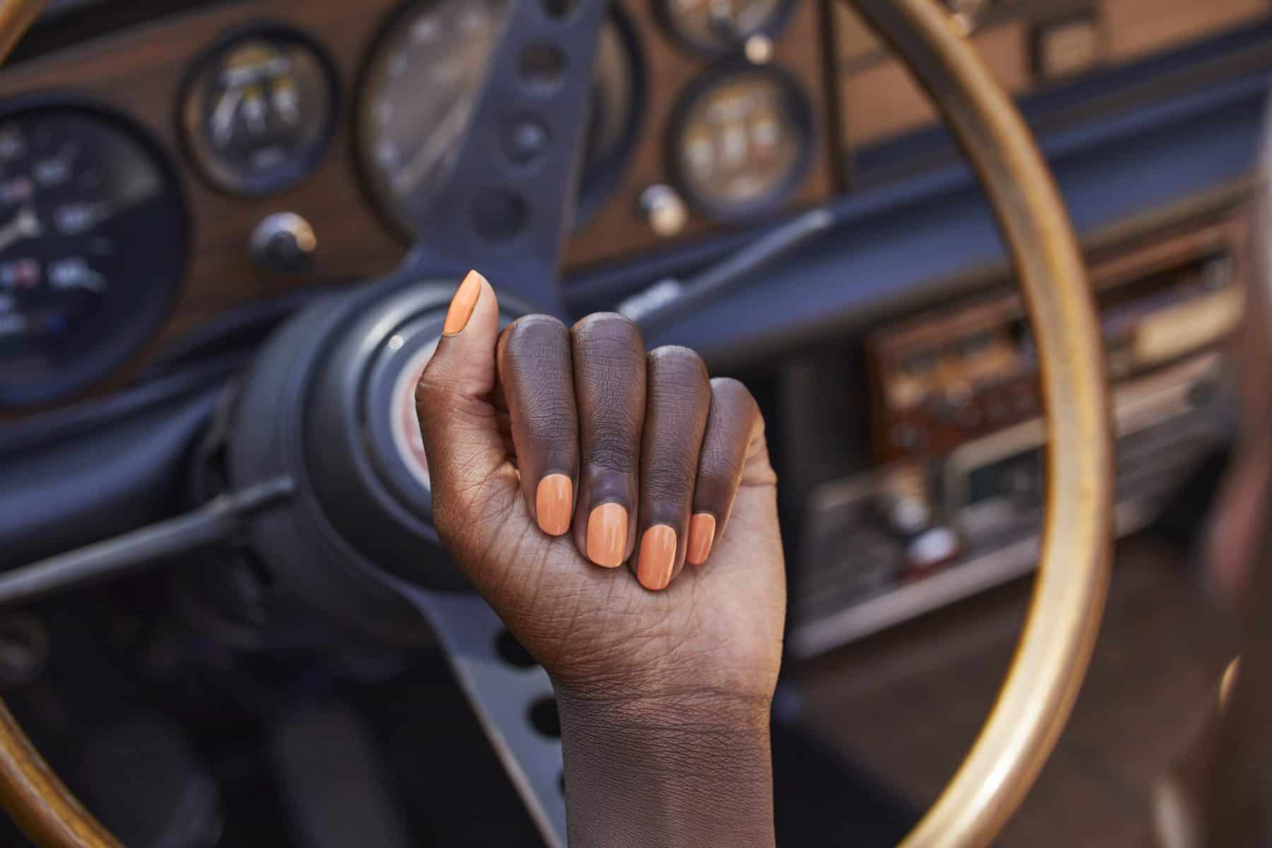 A hand with painted nails in the "Trading Paint" shade from the Palette Xbox collection from OPI