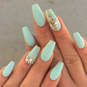 A light blue manicure adorned with jewels