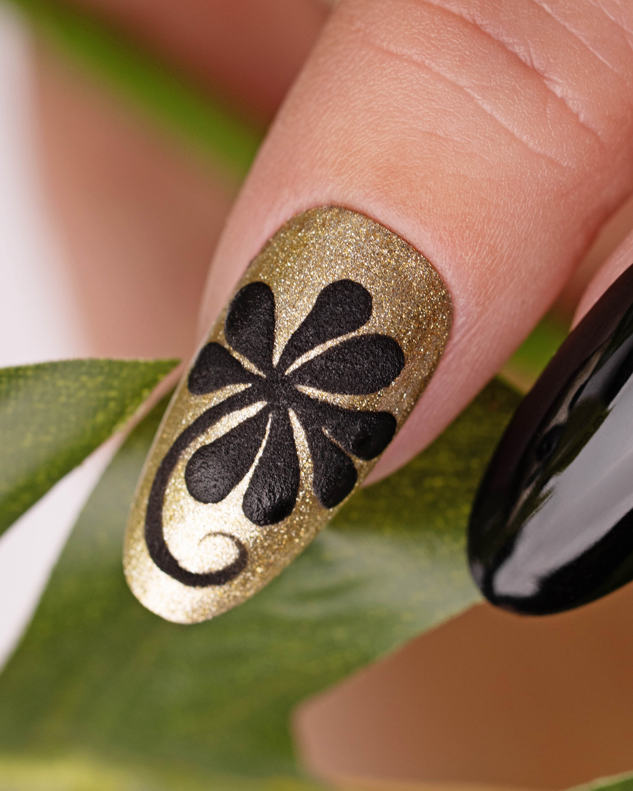 Black flower nail art on the gold nail polish