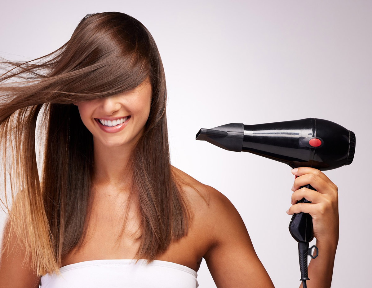 A woman with beautiful hair uses a hair dryer
