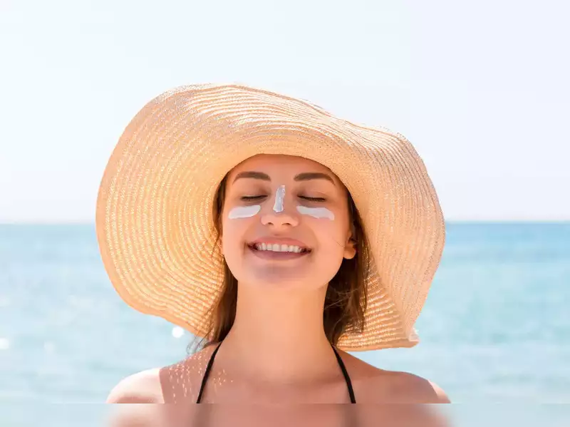 A closeup shot of a beautiful young woman spending some time at the beach wearing sunscreen on her face and a hat to protect her hair from the sun