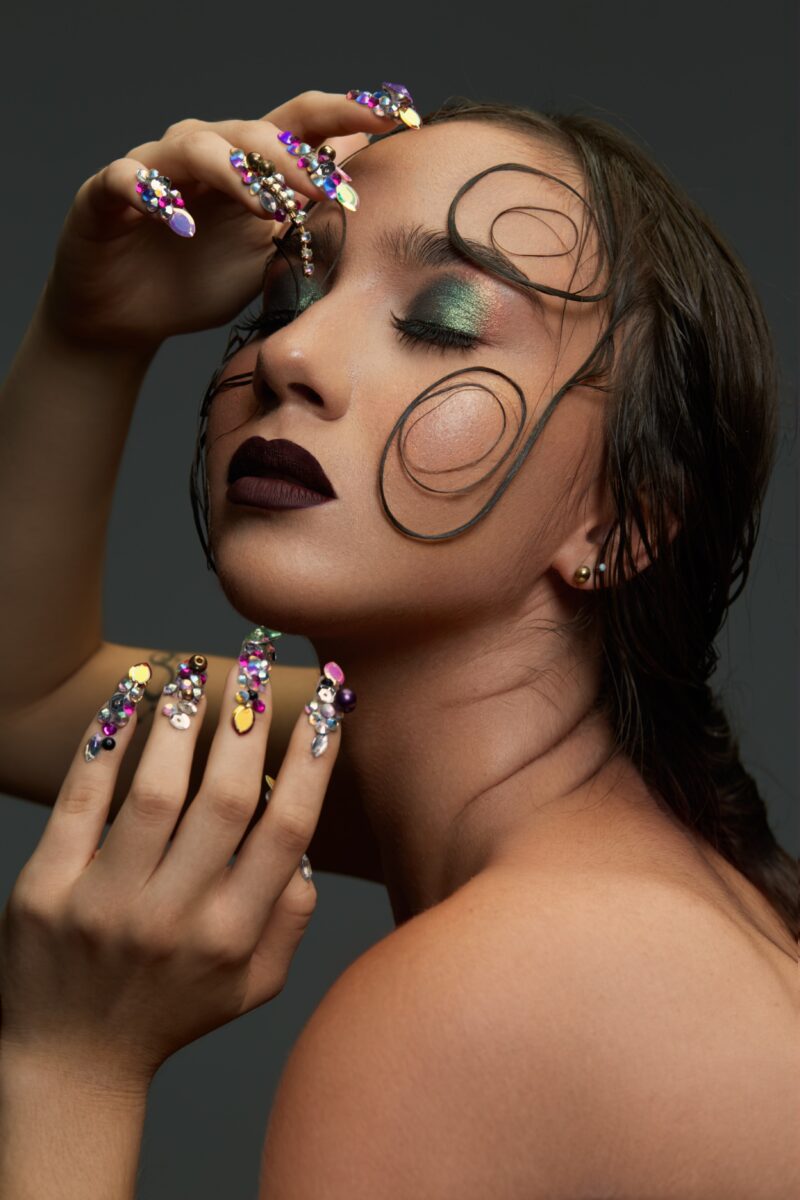 A beautiful woman closes her eyes, wearing amazing rhinestones on her nails.
