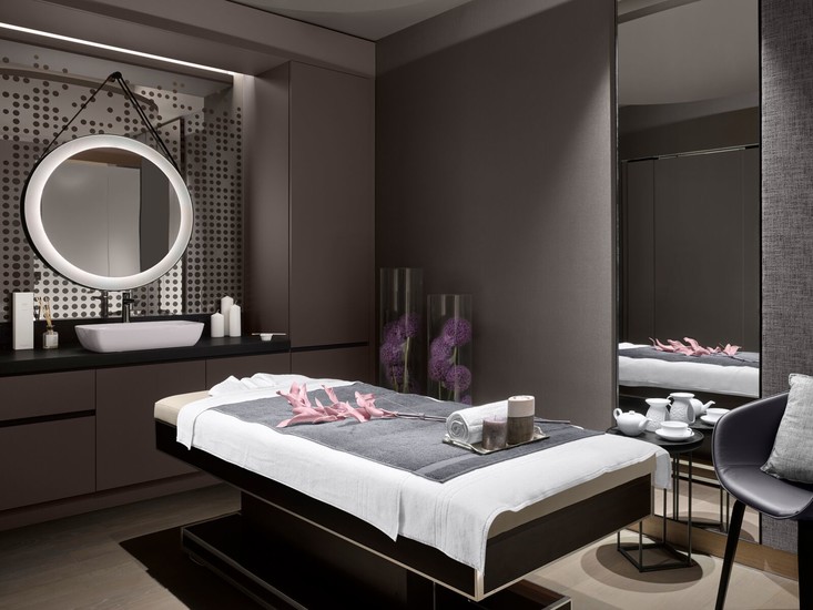 A clean room with a massage bed in a spa center and white and gray towels. Salon and spa disinfectants