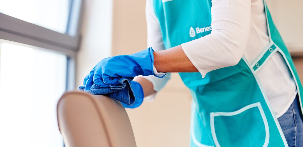 A faceless woman in a spa center wearing blue gloves is cleaning the couch. Salon and spa disinfectants