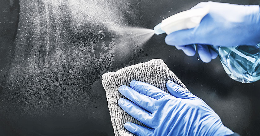 A faceless woman disinfects the spa center surfaces using vital spa disinfectants while wearing blue gloves. Salon and spa disinfectants