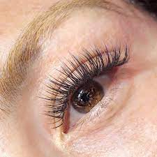 A close-up of a blond woman's brown eye with eyelashes from the JB Lashes brand