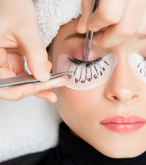 Woman getting eyelash extensions in a salon.