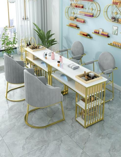 A nail salon boasts elegant gold table and chairs, with a wall-mounted nail polish display showcasing an array of vibrant nail colors.