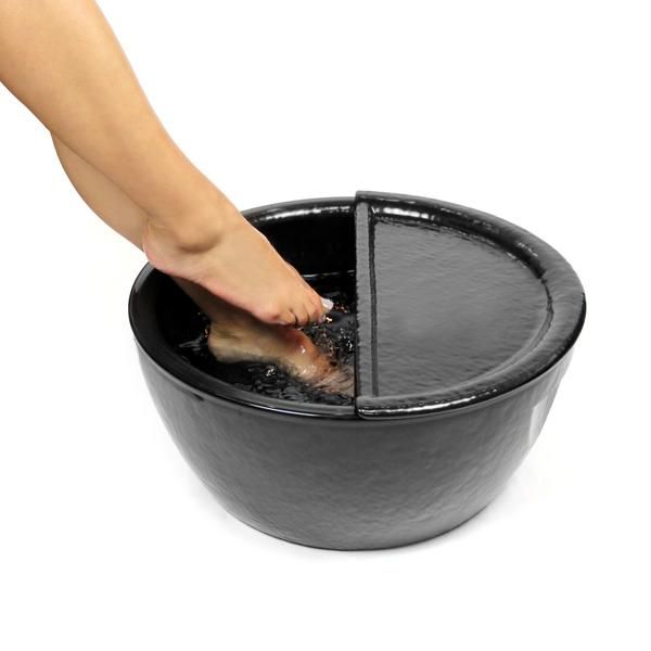 A woman's feet in a black pedicure bowl with a black footrest