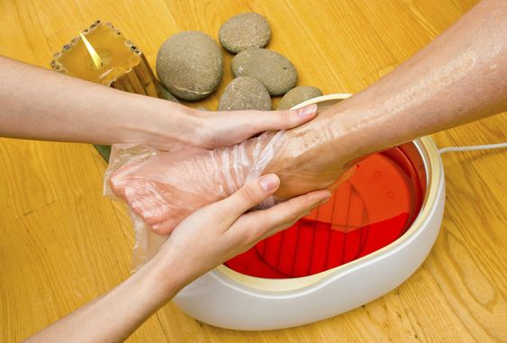 A woman's foot is being treated with a paraffin wax soak.