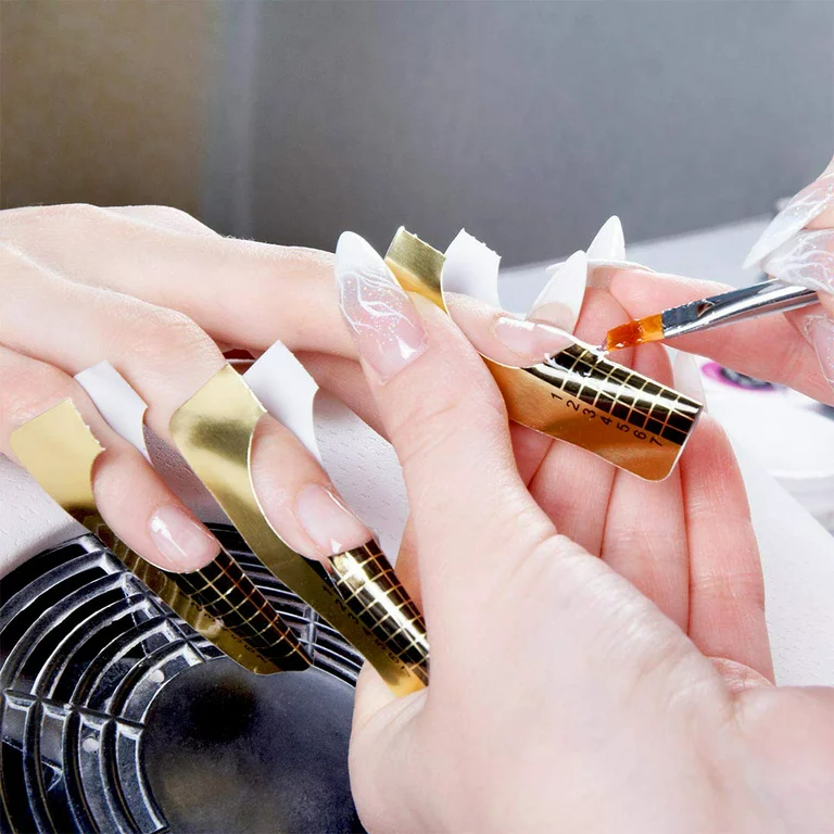 A faceless nail professional is putting the nail forms to the faceless client's nails. Sub-nail tools.