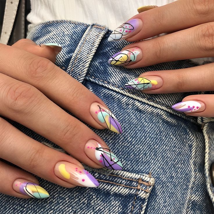 A woman wearing jeans pants with colorful nails featuring geometric pattern designs.