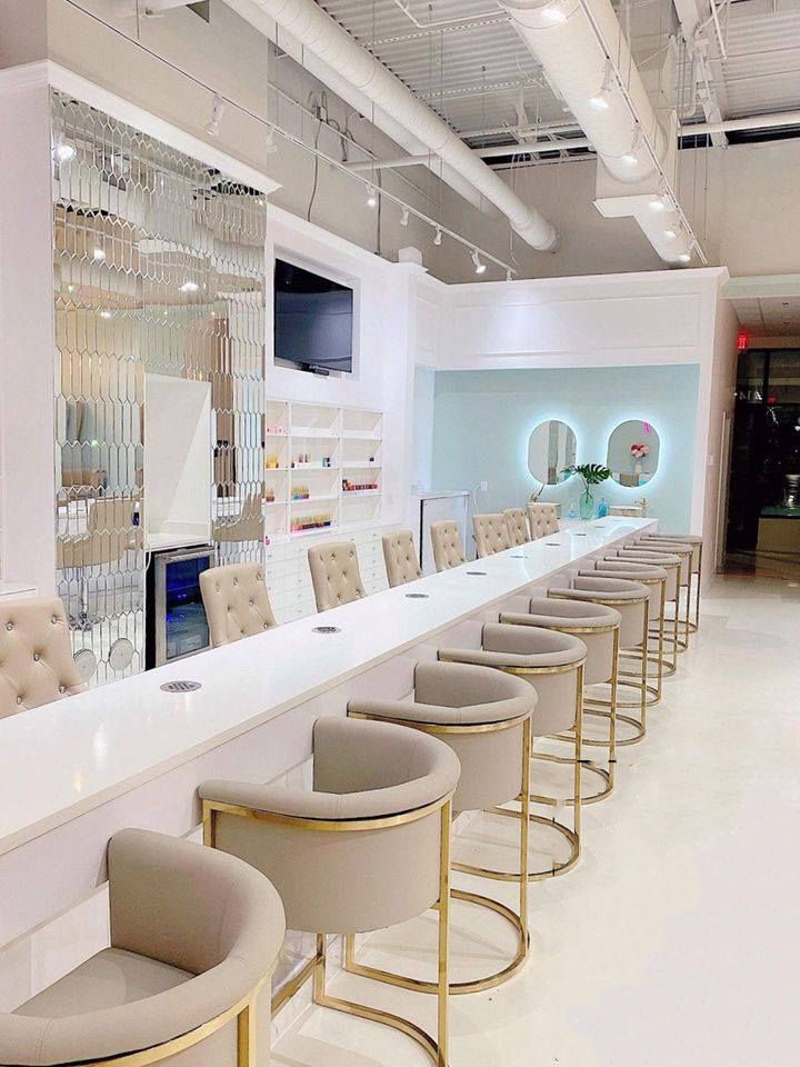 A nail salon with a simple, classy decoration theme with a long line of chairs and mirrors