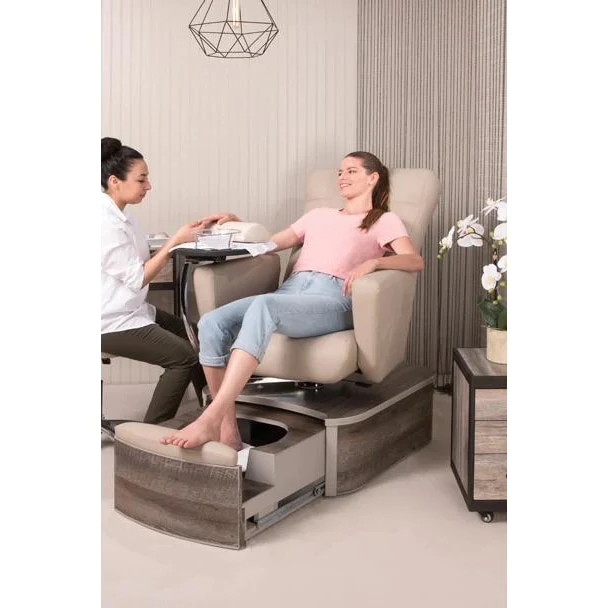 A delighted client sitting in a pedicure chair, receiving both a pedicure and a manicure from a professional nail technician.