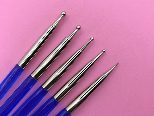 Nail art brushes and dotting tools on a purple background