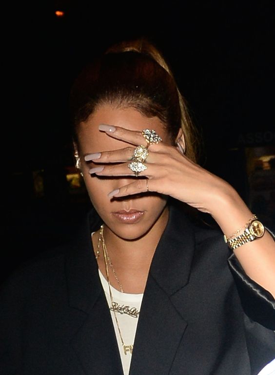 A close-up for Rihanna for her face and her long beige painted nails
