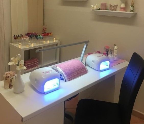 A manicure section featuring a table equipped with two LED nail lamps, a desktop lamp in the center, and designated positions for clients to place their hands while nail technicians attend to them. Desktop Lamps