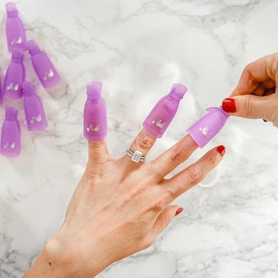 Woman with silver ring wearing finger cots, removing dip powder nails