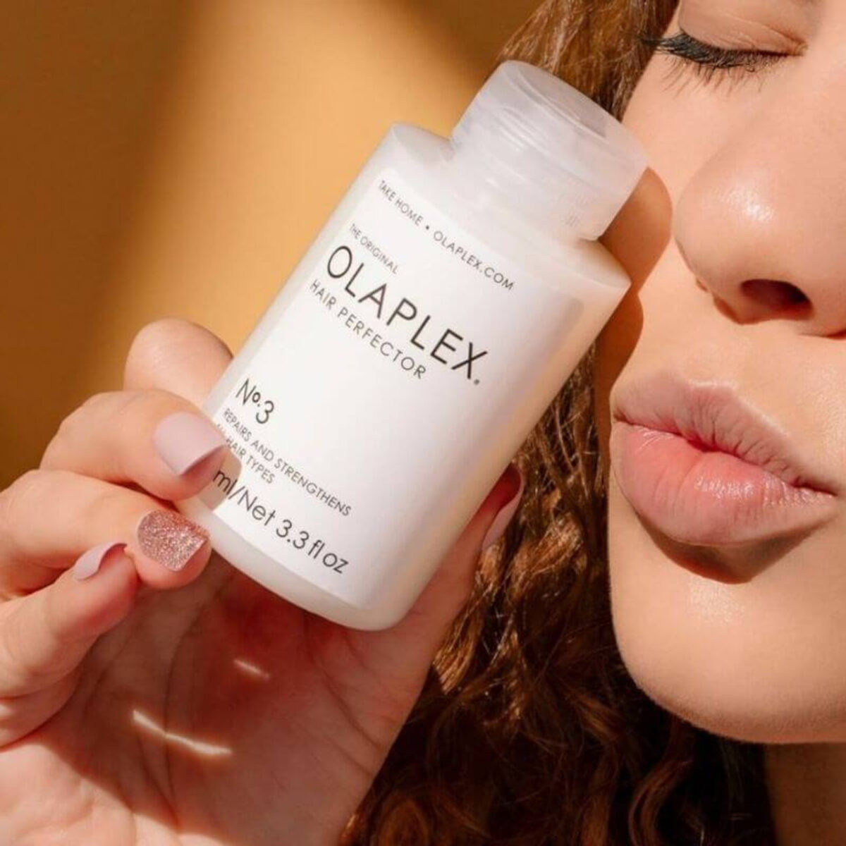 A woman is holding an Olaplex hair perfector