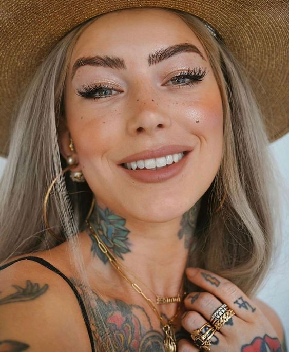A beautiful woman with tattoos and a hat wearing Ardell Lashes.