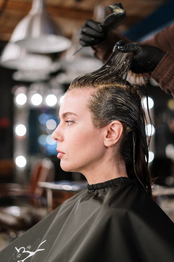 Hair professional doing a clients' hair with Henna
