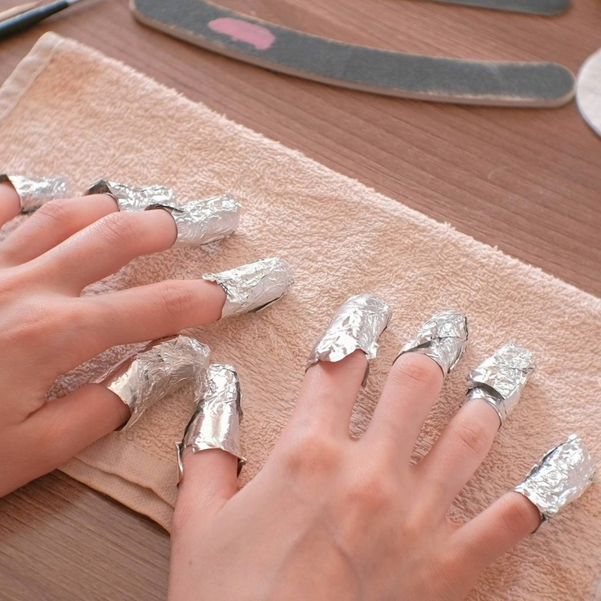 A woman's nails wrapped in nail foils for Shellac shade removal