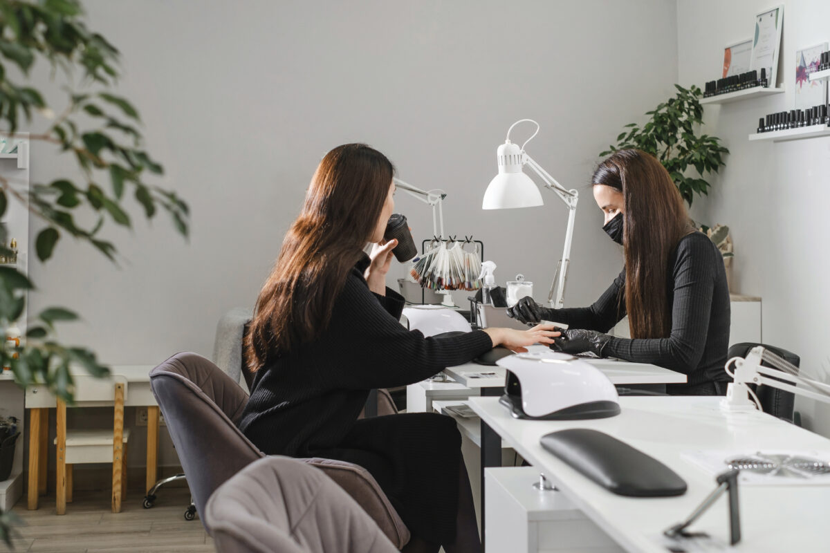 Female manicurist working on client nails in professional salon.