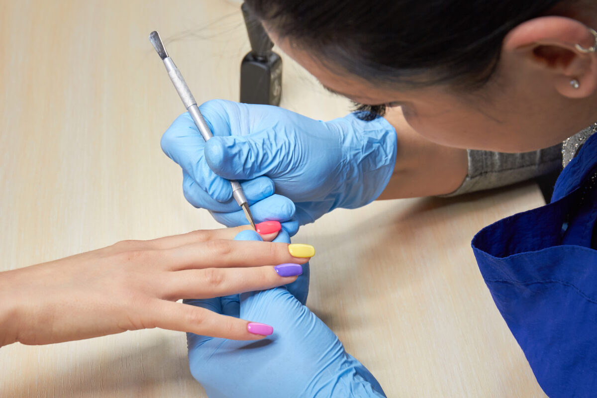 Young woman having manicure in nail salon. Colorful nails. Yellow, blue, pink and purple nails