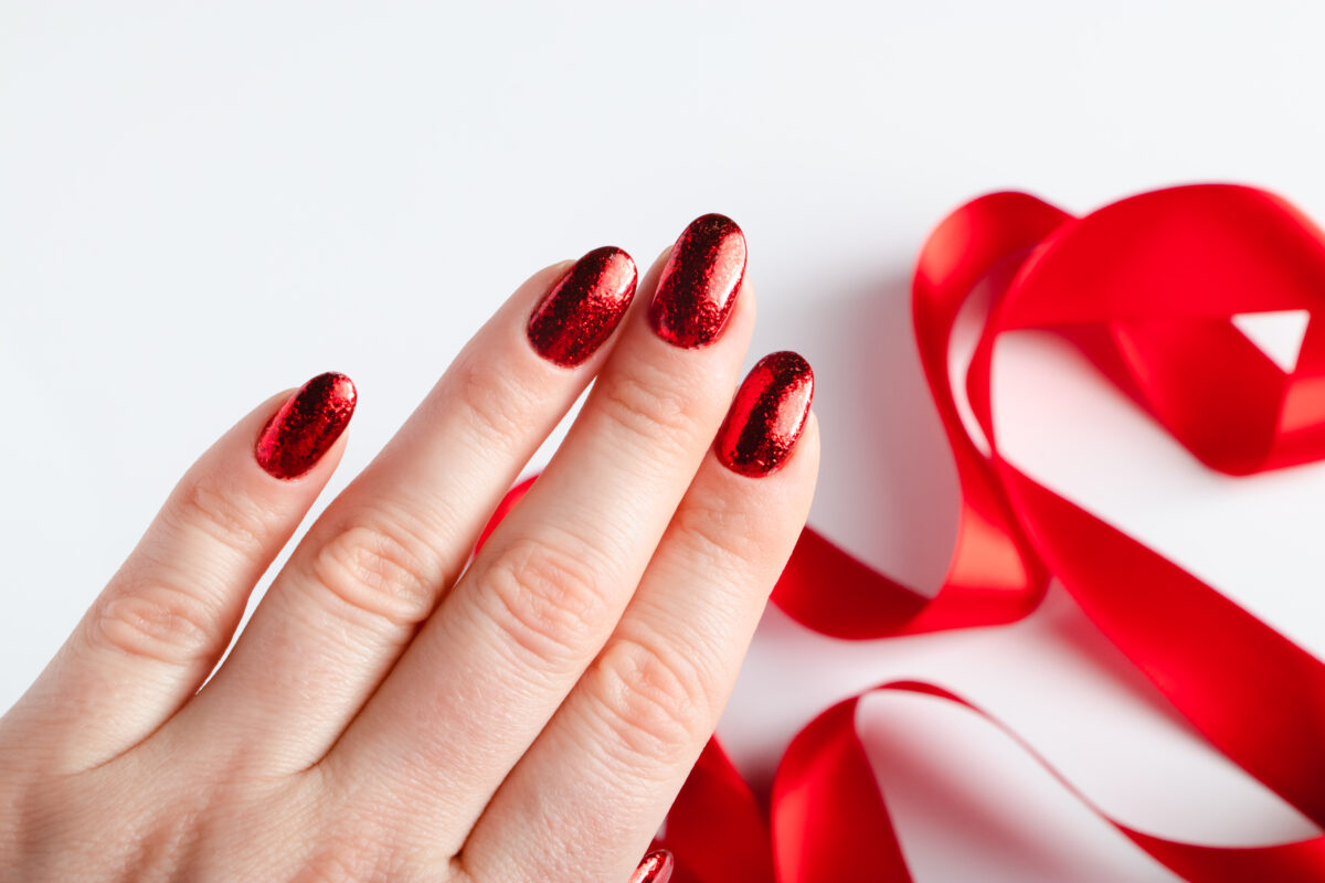 Womans hand with bright shiny manicure. Beautiful red nail polish. Work of master in nail salon.