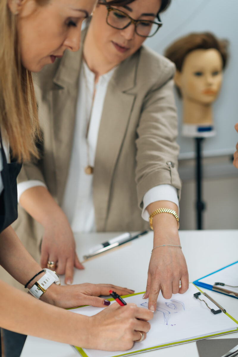 Cosmetology micro blading eyebrows education in beauty esthetic center. Female tattoo artist drawing eyebrow sketches with students