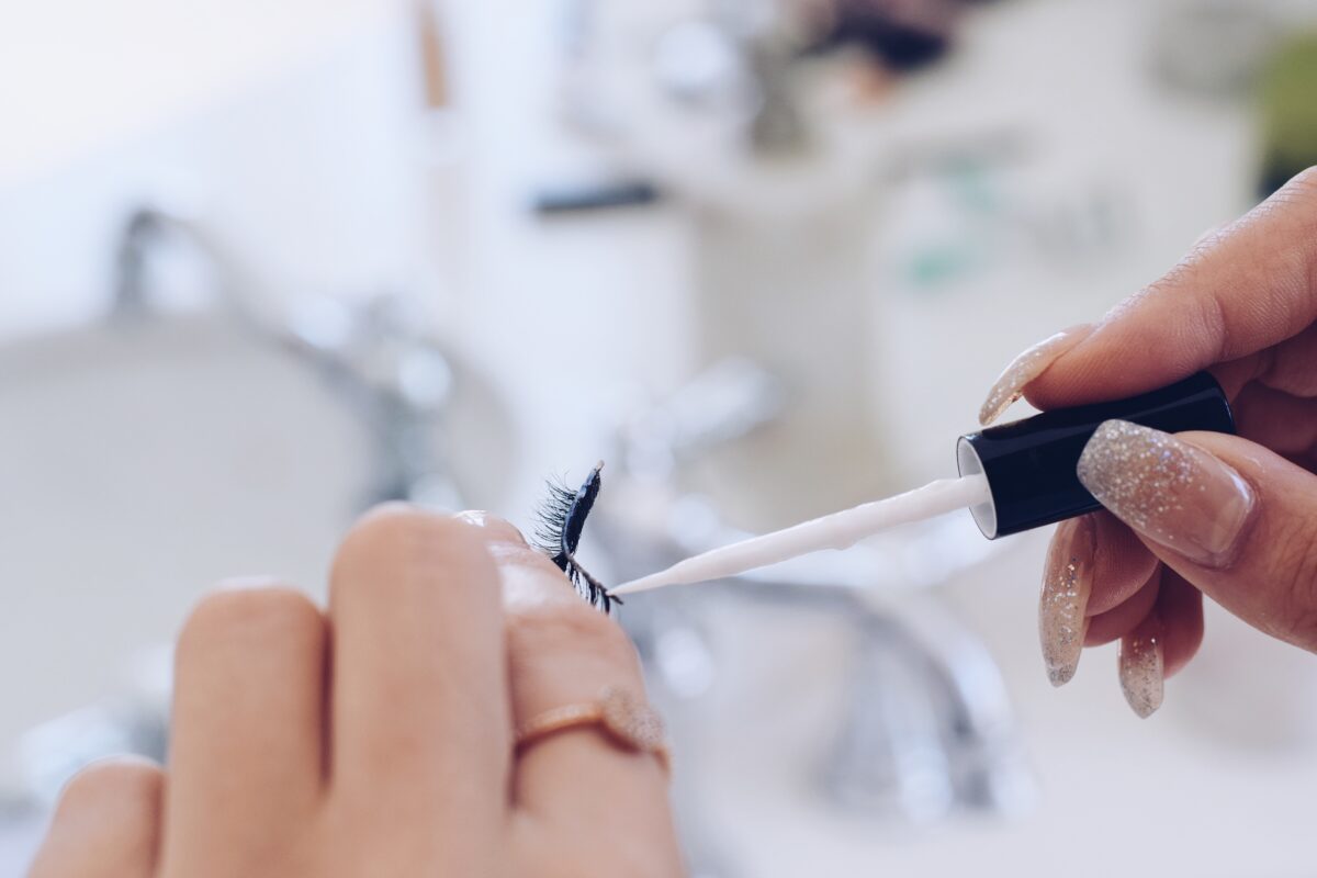 Girl applying glue to fake eyelashes