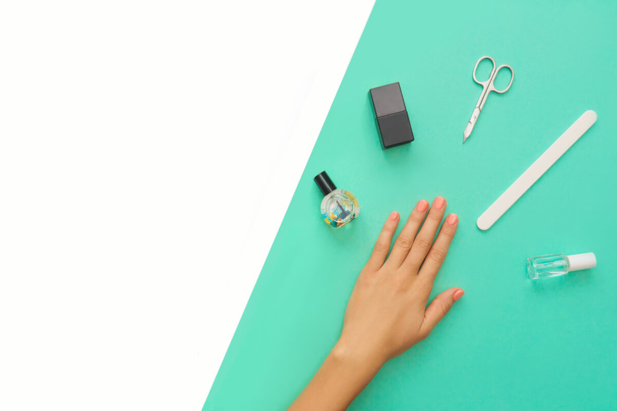 Beautiful manicure orange nails on the mint background with tools for manicure. Place for text.