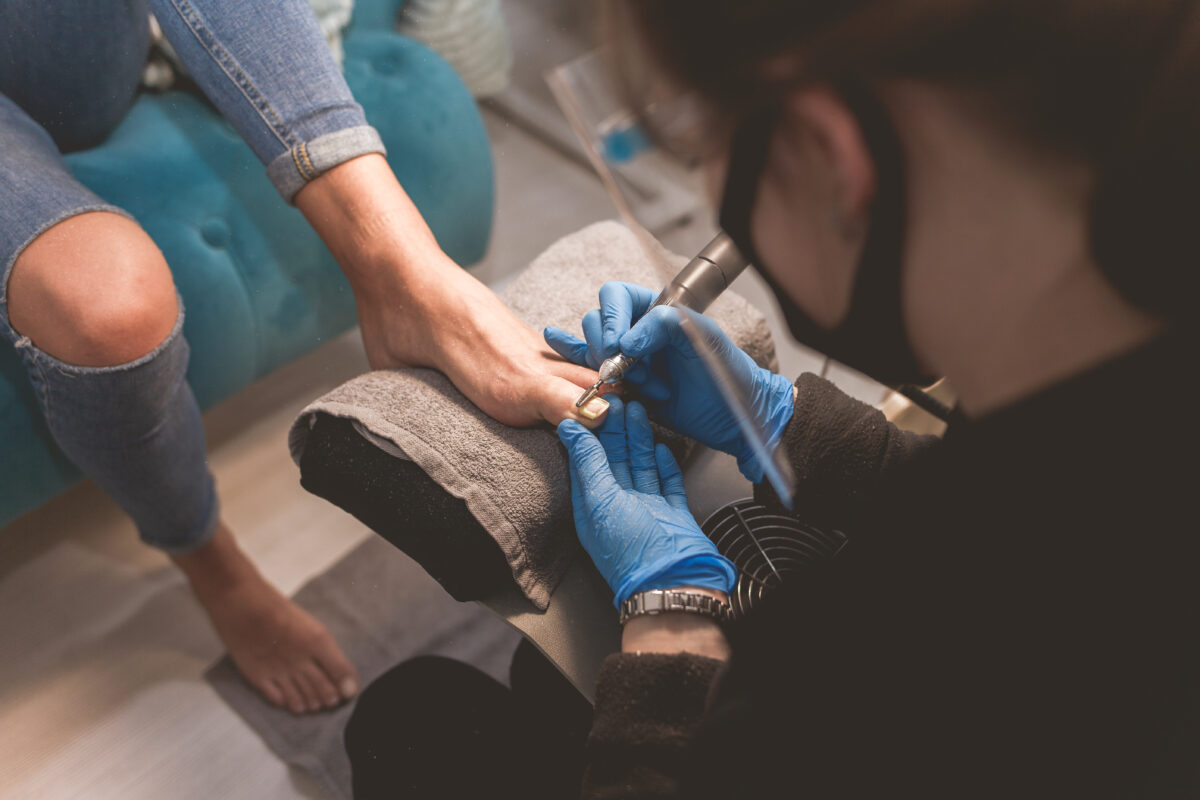 Pedicure master uses nail file drill for preparing nails for pedicure