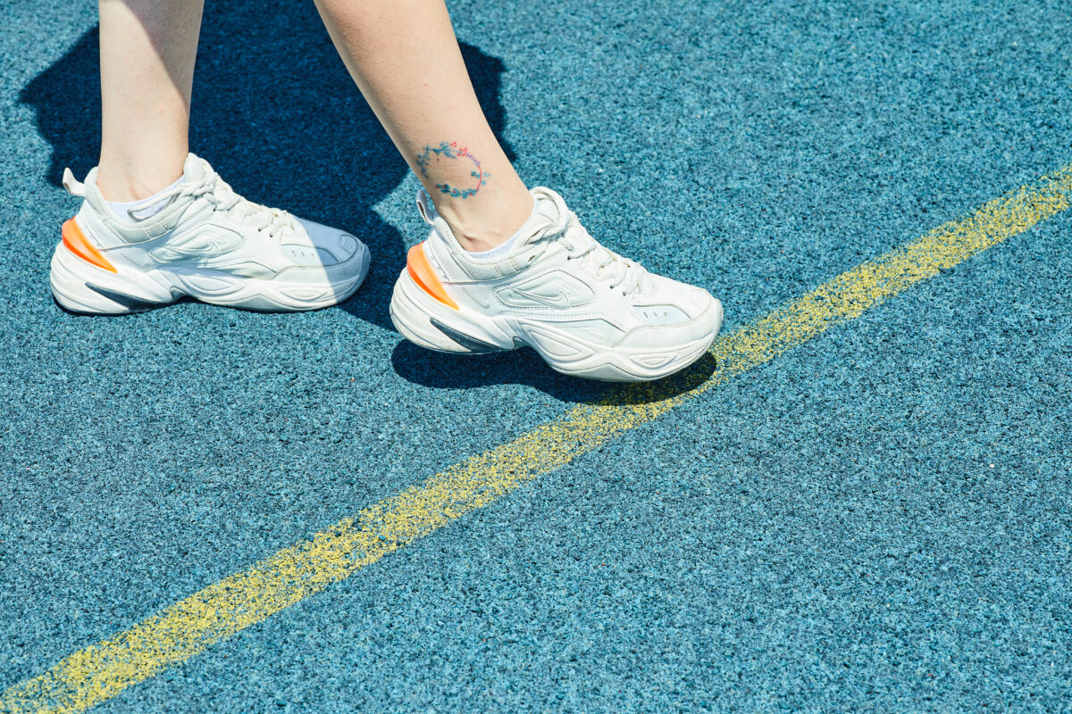 Woman wearing white sneakers on blue background.