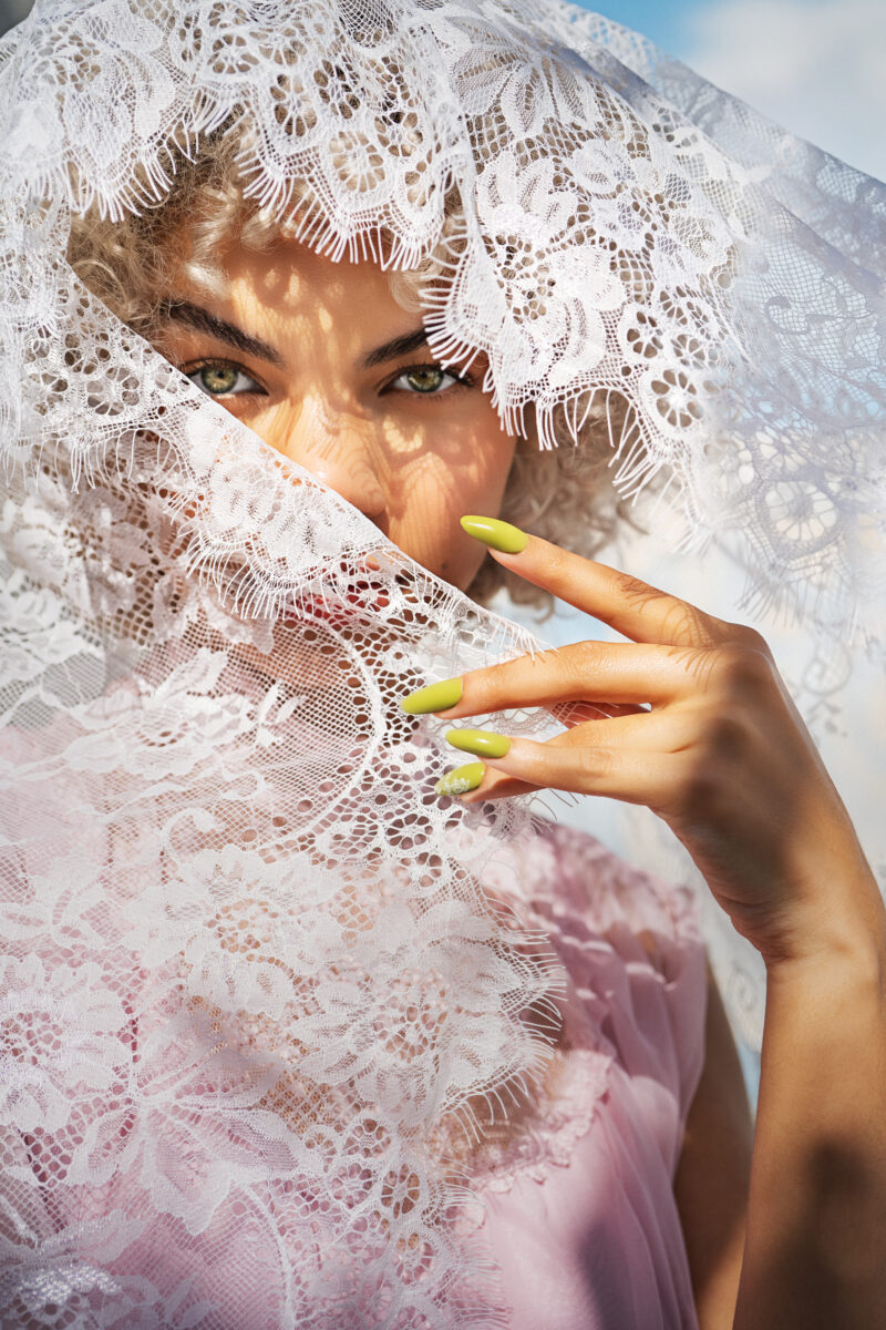 Gelish Spring 2024 nail collection. A beautiful woman with white hair wearing a white dress with green painted nails inspired from the soft green lace