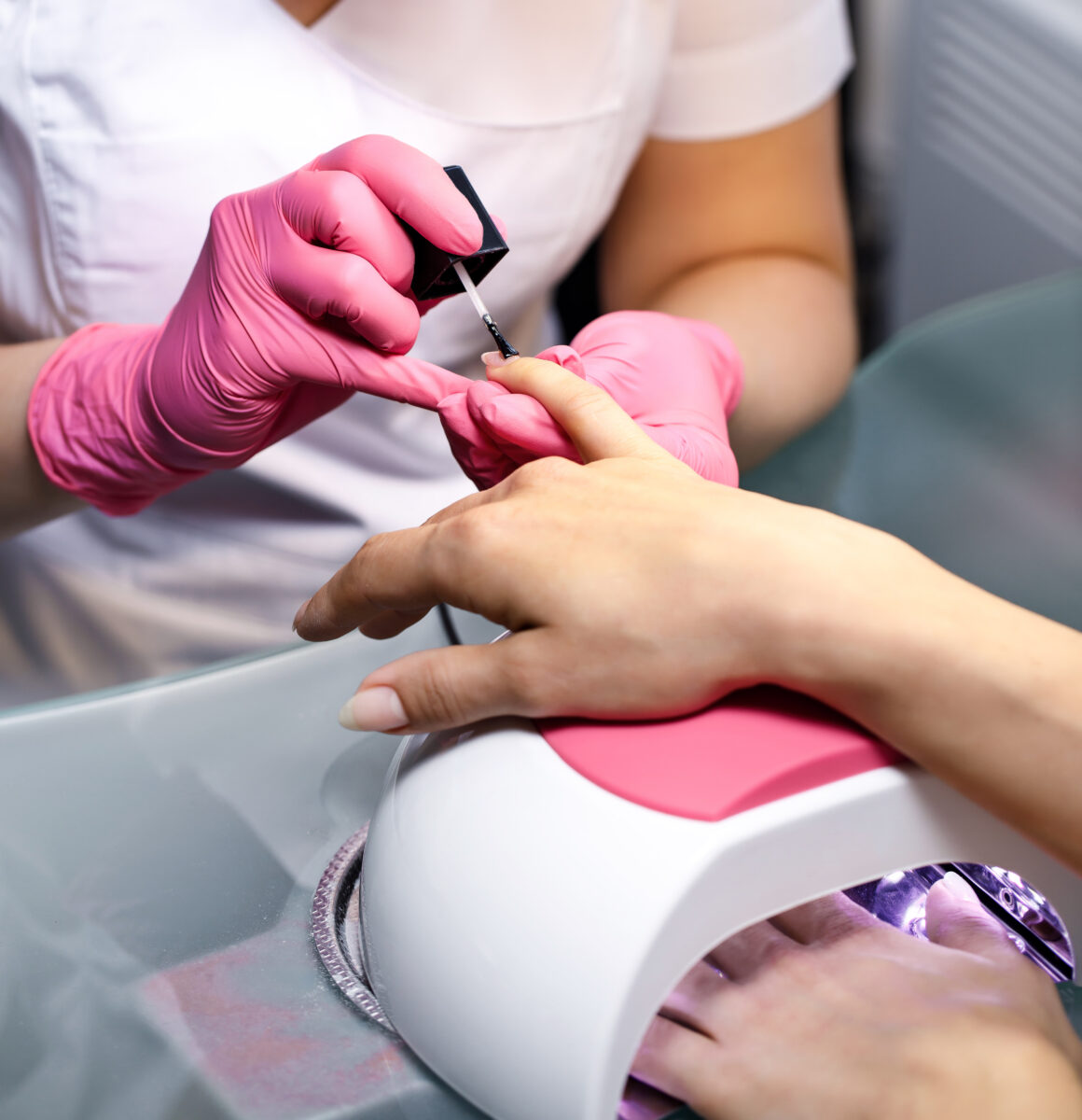 Beautician applying Polish nails to woman nails. manicure process