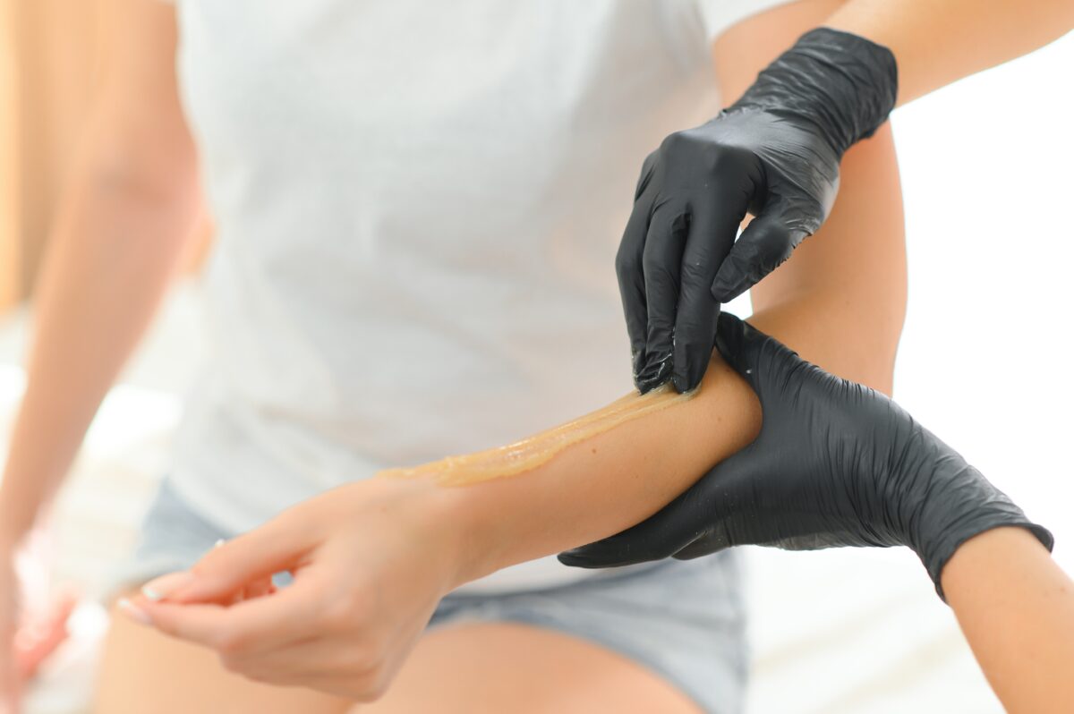 Sugar paste hair removal procedure - shugaring. Cosmetologist applies sugar paste to the hand.
