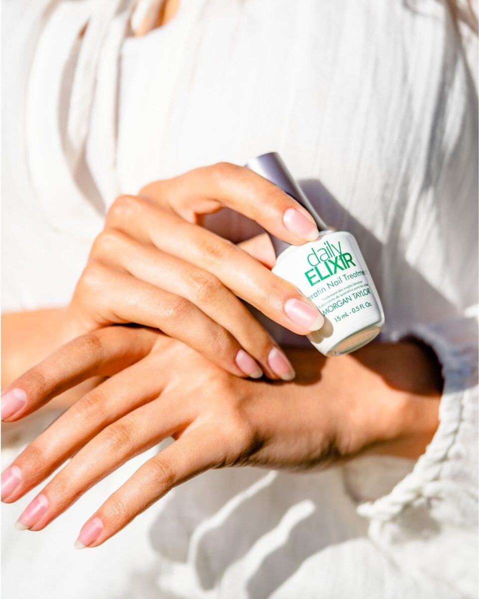 A faceless woman holding a dailyELIXIR Keratin Natural Nail Treatment bottle from Morgan Taylor