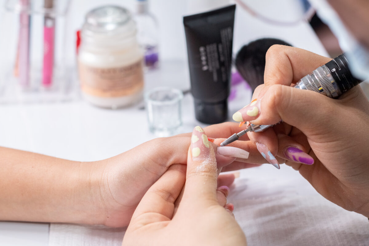 Close-up of hands filing a woman's nails with a nail file. Professional manicure service.