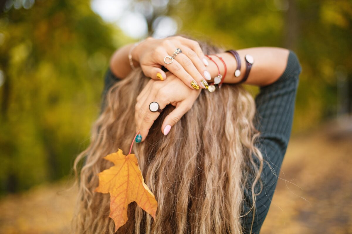 Girl with curly hair on a background of autumn nature. Close-up photo, details. Beautiful decoration. CND Fall 2024 nail polish collection