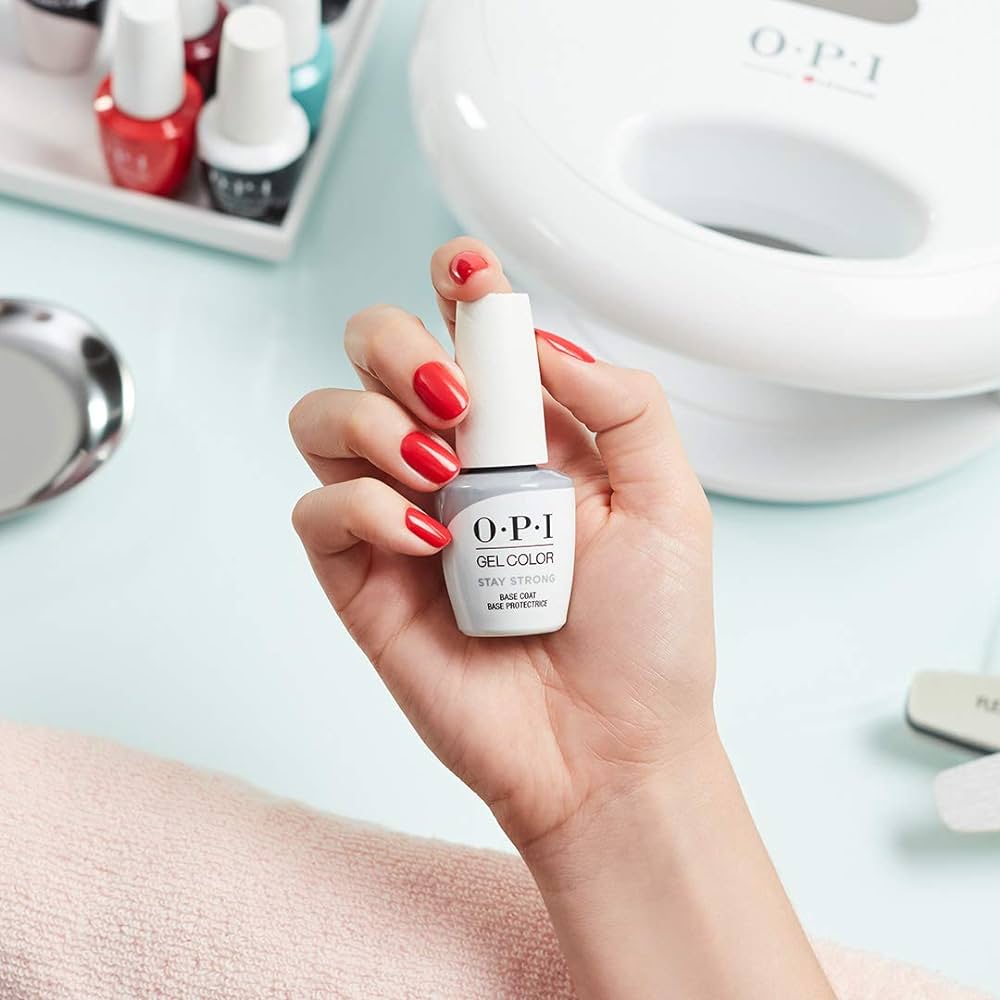 A faceless woman with red-painted nails holding an OPI Gel Color Stay Strong base coat bottle. Strengthening Base Coat