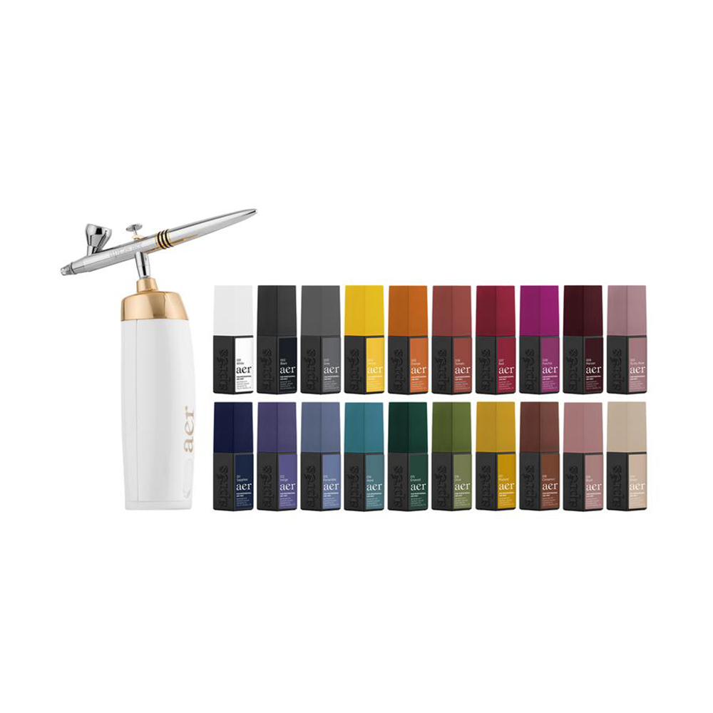 A collection of nail products. The arrangement includes a white nail airbrush with a gold and silver pump, labeled ‘Aprés. Next to it are small, colorful bottles with different nail polish shades.