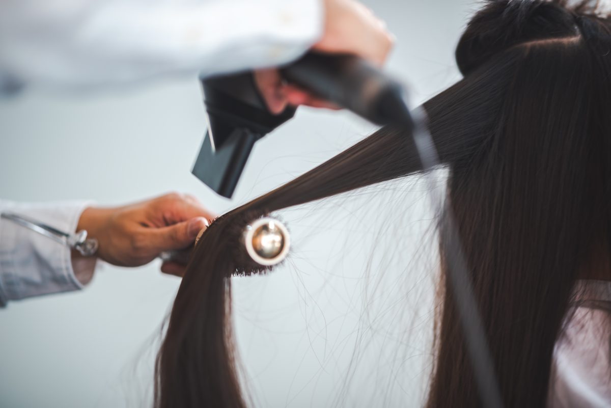 Asian Hairdresser giving treatment and barber occupation service, Professional hairstylist combing and using scissors cut woman's hair to young beautiful customer girl in beauty salon