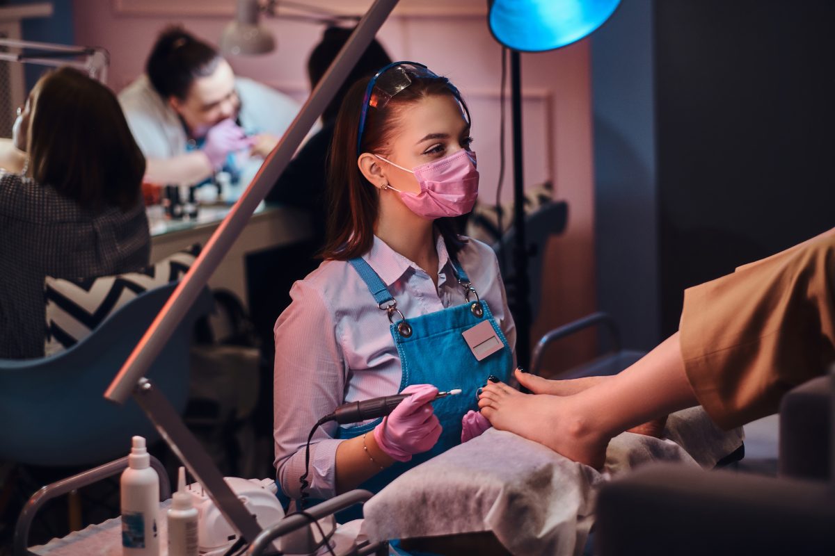 Process of pedicure at busy nail studio. Customer is getting good service from beautiful diligent master. Manicure services. Pedicure service.