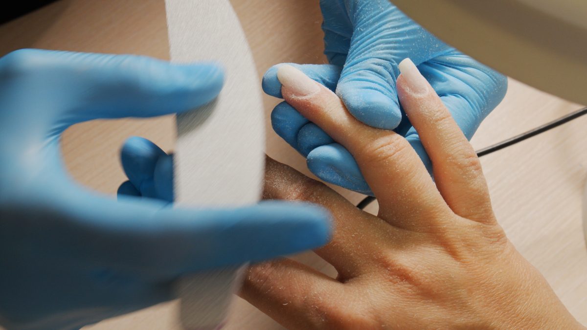 Nail care at home. Process of nail treatment in a nail salon. A view from behind the nail master shoulder of the nail care process.