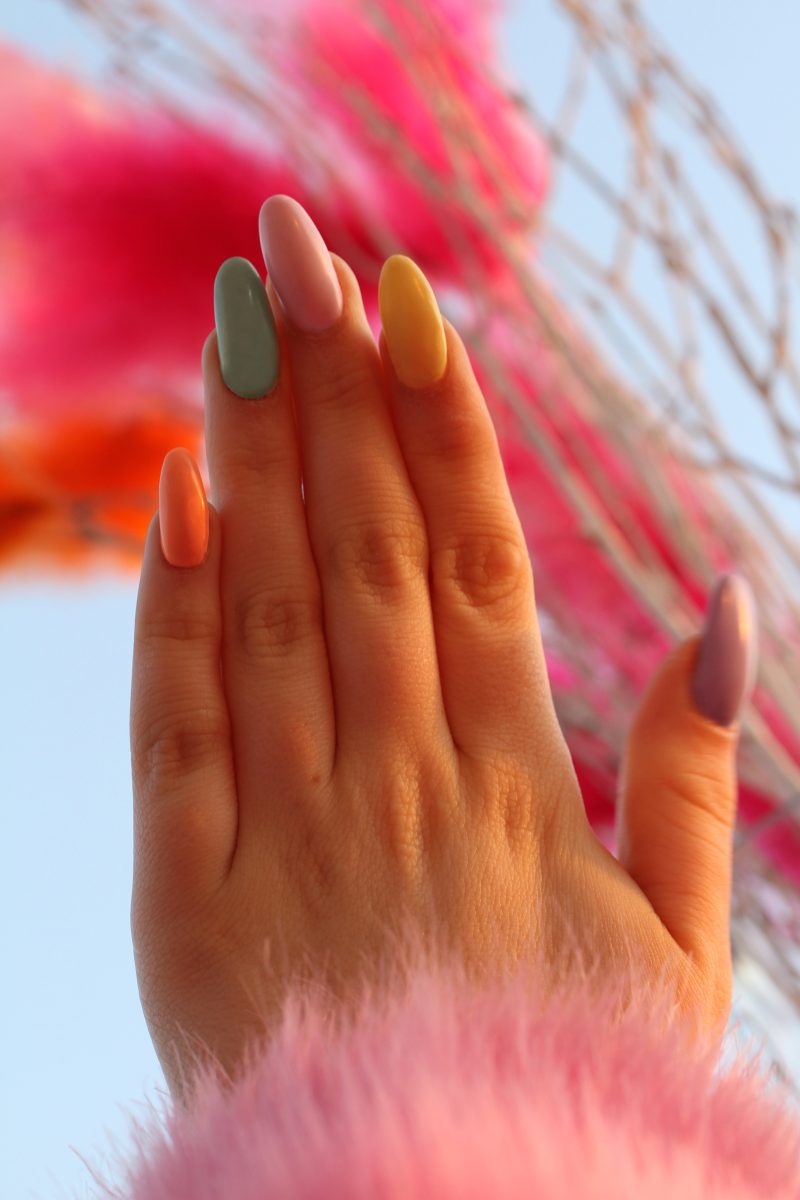 Colorful long painted nails featuring baby blue, yellow, pink, orange, and purple shades.