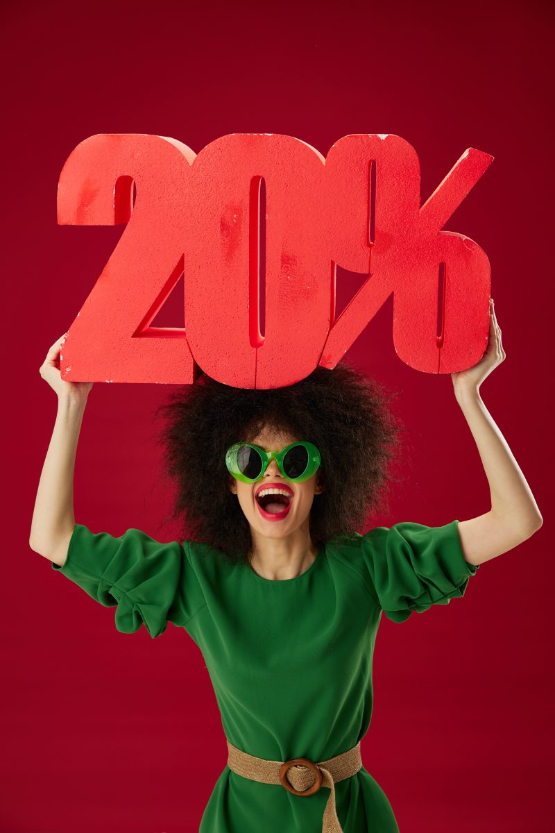 Positive young woman curly hairstyles green dress twenty percent discount color background unaltered. High quality photo.