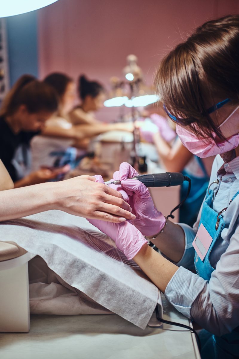 Process of manicure at beauty salon with two attractive happy women. Manicure services. Manicure pricing.